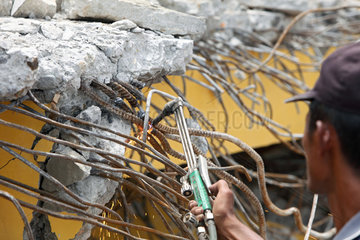 Padang  Indonesien  mit einem Schneidbrenner werden Stahlverstrebungen aus dem Beton geschnitten