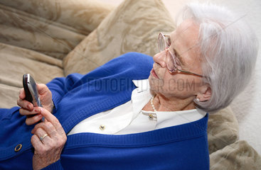 Berlin  Deutschland  eine alte Frau liest eine SMS auf ihrem Handy
