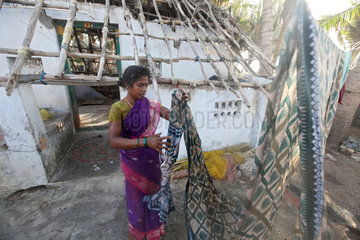 Kokilamedu  Indien  eine Frau haengt Waesche vor ihrem zerstoerten Haus auf