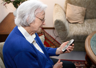 Berlin  Deutschland  eine alte Frau liest eine SMS auf ihrem Handy