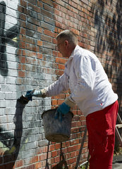 Berlin  Deutschland  Entfernung von Graffiti an einer Backsteinmauer