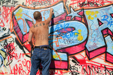 Berlin  Deutschland  Mann besprueht einen Mauerabschnitt