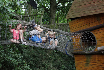 Marlow  Deutschland  Kinder auf einem Spielplatz sitzen in einer Gitterroehre