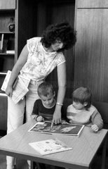 Berlin  DDR  Vorschulkinder schauen sich mit einer Bibliothekarin ein Buch an