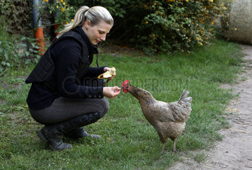 Neuenhagen  Deutschland  Frau fuettert ein Huhn mit einem Stueck Banane