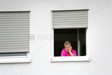 Beckingen  Deutschland  Frau mittleren Alters schaut aus dem Fenster