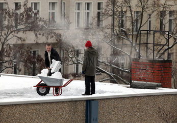 Berlin  Deutschland  Mann schippt Schnee von einem Flachdach