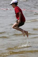 Berlin  Deutschland  Junge huepft im Wasser herum