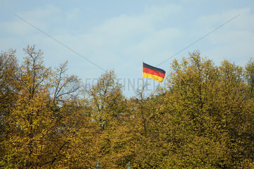 Berlin  Deutschlandflagge hinter einem Waeldchen