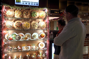 Hong Kong  China  Maenner stehen vor einer Vitrine mit den Angeboten eines Restaurants