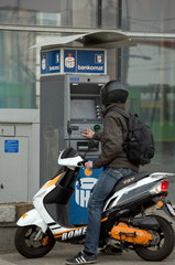 Posen  Polen  ein junger Rollerfahrer an einem Geldautomaten der Bank PKO