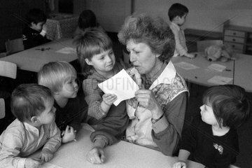 Berlin  DDR  Kind zeigt seiner Erzieherin im Kindergarten ein selbstgemaltes Bild