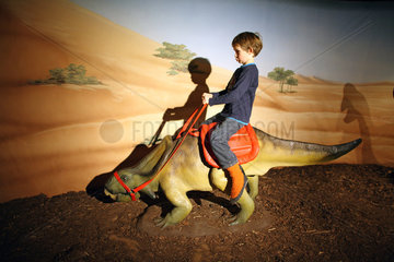 Berlin  Deutschland  Kind reitet auf einem Dinosaurier in der Alexa Kindercity