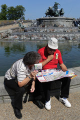 Kopenhagen  Daenemark  Touristen sitzen am Gefion Brunnen ueber Strassenkarten