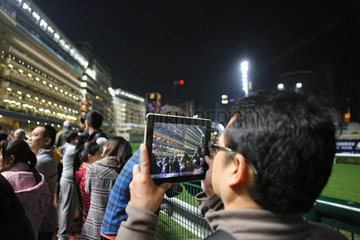 Hong Kong  China  Mann filmt mit seinem Tablet-PC auf der Galopprennbahn Happy Valley
