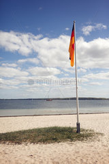 Eckernfoerde  Deutschland  Blick ueber die Eckernfoerder Bucht mit Deutschlandfahne am Strand