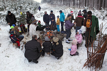 Neuenhagen  Deutschland  Menschen sitzen im Winter an einem Lagerfeuer im Wald
