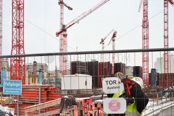 erlin  Deutschland  Bauarbeiter befestigt Schild am Bauzaun auf der Baustelle Wertheim-Areal