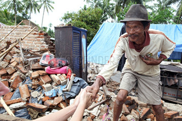Sungai Rambai  Indonesien  ein betroffener aelterer Mann vor seinem zerstoertem Haus