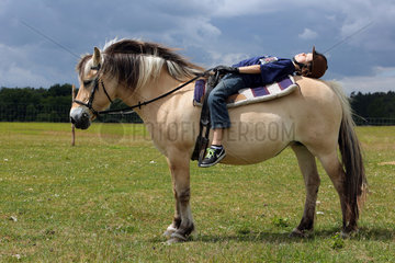 Neu Kaetwin  Deutschland  Junge schlaeft auf seinem Pferd