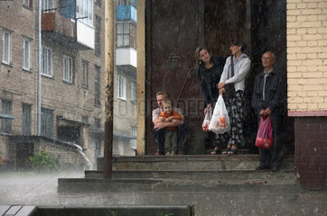 Scucyn  Weissrussland  Menschen stellen sich in einem Hauseingang bei Regen unter