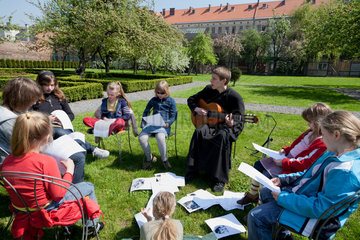 Krakau  Polen  Priester singt religioese Lieder mit einer Gruppe von Maedchen