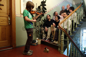 Berlin  Deutschland  ein Junge gibt ein Treppenkonzert vor der Grossfamilie in ihrem Mehrgenerationenhaus