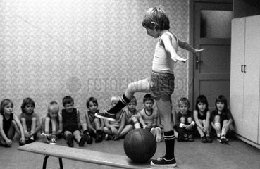 Berlin  DDR  kleiner Junge steigt im Sportunterricht auf einer Bank ueber einen Medizinball