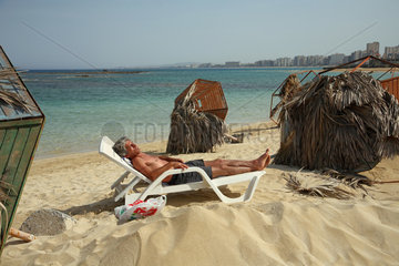 Famagusta  Tuerkische Republik Nordzypern  ein Mann am Strand zwischen umgefallenen Sonnenschirmen