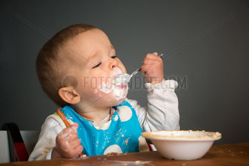 Berlin  Deutschland  ein Kleinkind mit Schnute isst Joghurt mit einem Loeffel