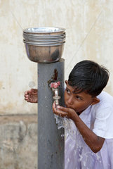 Navatkerny  Sri Lanka  ein Maedchen trinkt sauberes Trinkwasser von einer Wasserpumpe