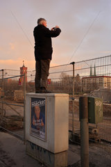 Berlin  Deutschland  Mann steht auf einem Schaltkasten und fotografiert