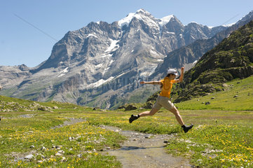 Lauterbrunnental  Schweiz  Frau springt ueber einen Gebirgsbach