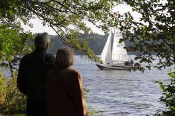 Berlin  Deutschland  aelteres Ehepaar schaut zu einem Segelboot auf dem Langen See