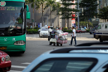 Shenzhen  China  ein Mann zieht einen schwer beladenen Karren