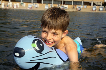 Berlin  Deutschland  ein Junge schwimmt lachend mit seinem Gummitier im Wasser