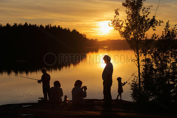 Silvkoparen  Schweden  eine Familie sitzt am Ufer eines Sees bei Sonnenuntergang