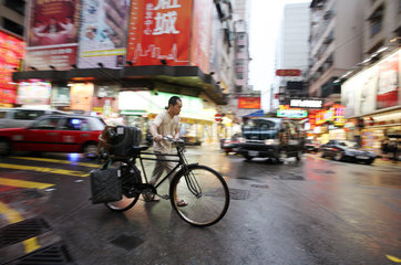 Hong Kong  China  Mann schiebt sein Fahrrad ueber die Strasse