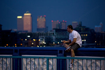 London  Grossbritannien  Mann sitzt mit Handy auf der Tower Bridge an der Themse