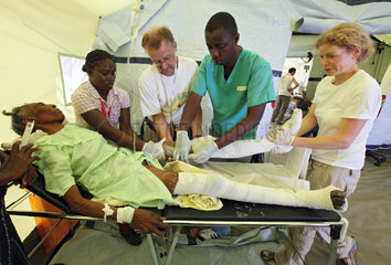 Carrefour  Haiti  Aerzte und Krankenschwester gipsen die Beine einer Frau ein