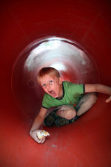 Berlin  Deutschland  Junge krabbelt durch einen Tunnel auf einem Kinderspielplatz