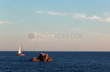 Santa Margherita di Pula  Italien  Segelboot hinter einem Felsen auf dem Meer