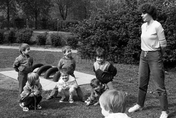 Berlin  DDR  Kindergartenkinder spielen mit ihrer Erzieherin im Freien