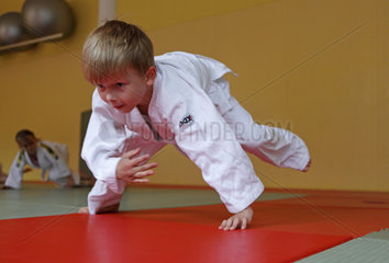 Berlin  Deutschland  Junge macht eine Vorwaertsrolle in einem Judokurs