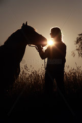 Oberoderwitz  Deutschland  Silhouette  Frau und Pferd bei Sonnenaufgang im Portrait