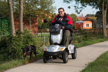 Sehnde  Deutschland  ein Mann unterwegs mit Elektromobil und Hund im Ortsteil Ilten