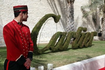 Dubai  Vereinigte Arabische Emirate  Hotelpage steht vor einem aus Moos geformten Logo des Juweliers Cartier