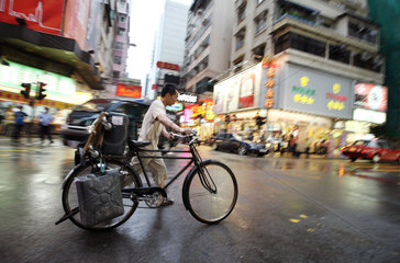 Hong Kong  China  Mann schiebt sein Fahrrad ueber die Strasse