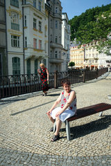 Karlsbad  Tschechische Republik  eine Frau sitzt auf einer Bank in der Altstadt