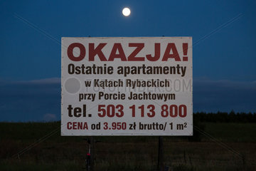 Polen  Mikoszewo  Plakat wirbt fuer Immobilien an der Ostsee